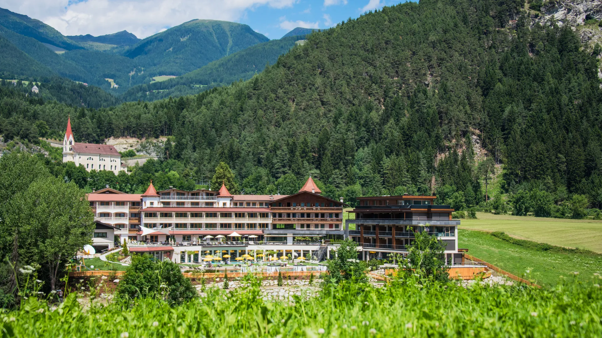 Hotel Kronblick eingebettet in grünes Alpental bei Kiens mit bewaldeten Berghängen